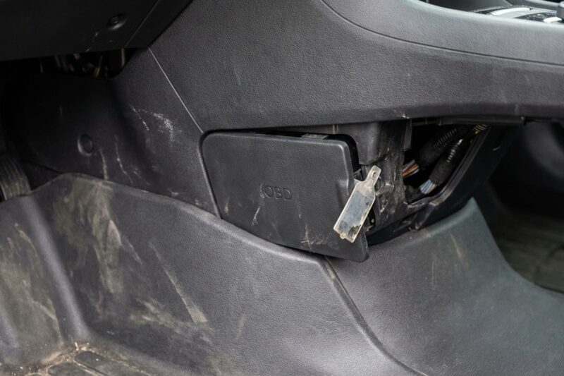 Why is the OBD2 port often blocked or inaccessible on Tesla and other EVs?